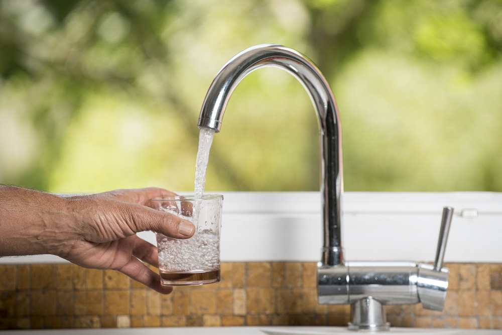 Demarches-eau-et-assainissement photo d'un avant bras avec un verre qui est en cours de remplissage à un robinet