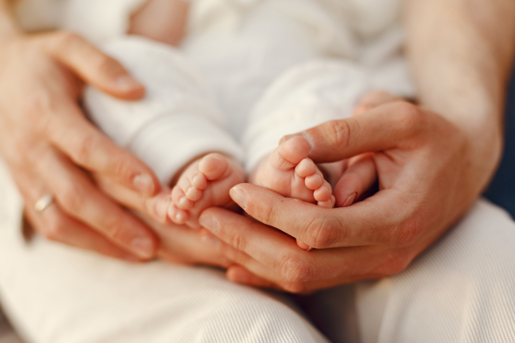 Photo de mains adultes soutenant les pieds nus d'un bébé