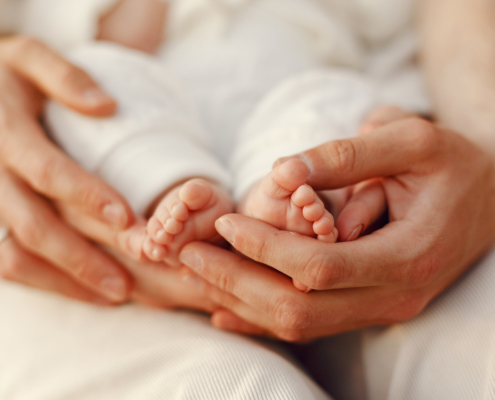 Photo de mains adultes soutenant les pieds nus d'un bébé